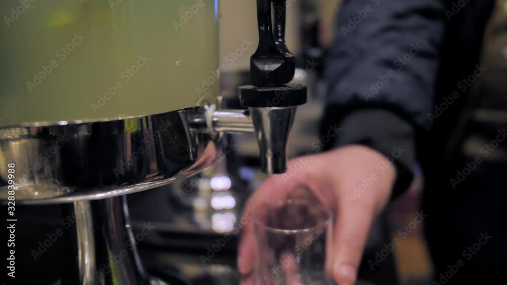 Man pouring beverage from dispenser at the lobby of a hotel, close up. Man pouring beverage from dispenser at the lobby of a hotel, close up.