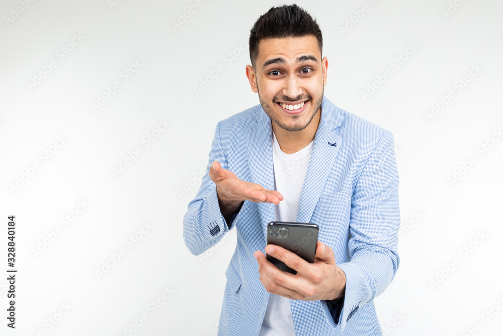 office brunette man in a jacket smilingly points to the screen of a gadget about a good offer of purchase on a white background office brunette man in a jacket smilingly points to the screen of a gadget about a good offer of purchase on a white background