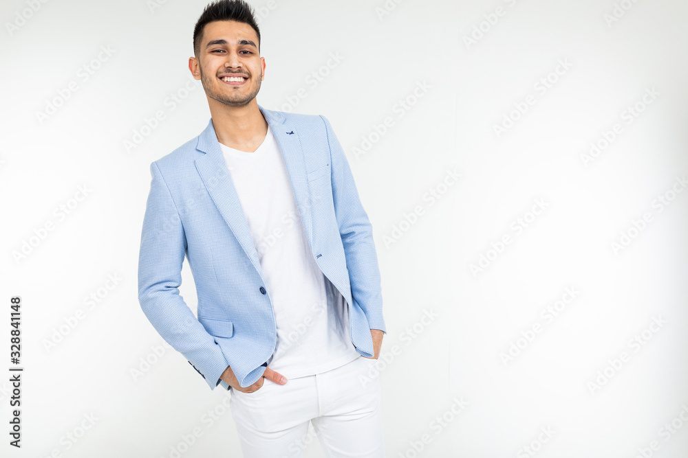 handsome guy in a blue jacket with a beautiful smile tucked his hands in pants on a white isolated background with copy space handsome guy in a blue jacket with a beautiful smile tucked his hands in pants on a white isolated background with copy space