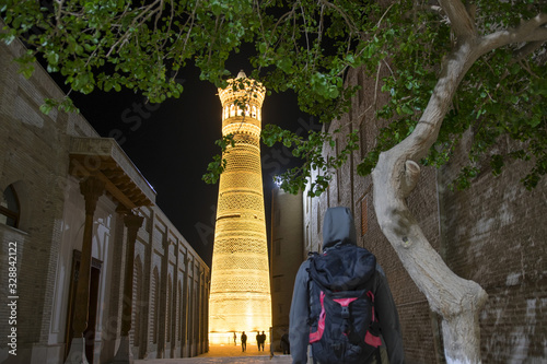 A tourist with backpack in front of Great Minaret of the Kalon and Kalon (Kallan) Mosque. Bukhara, Uzbekistan, Central Asia. photo