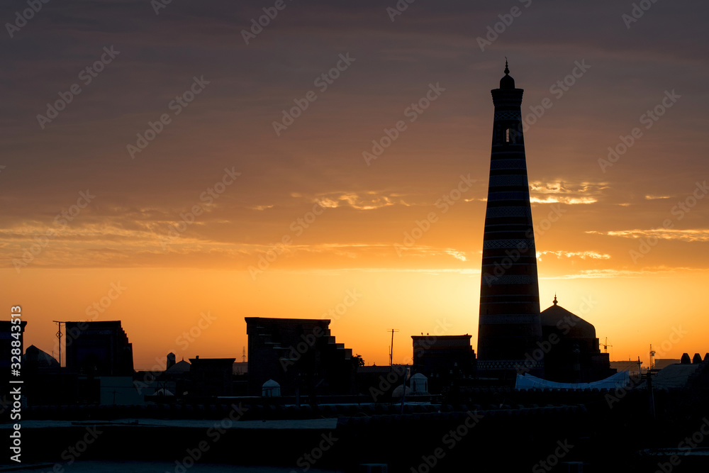 Sunrise view at Itchan Kala (old or inner town) and Islam Khoja Minaret, one of the most popular touristic attraction in the city. Khiva, Uzbekistan, Central Asia.