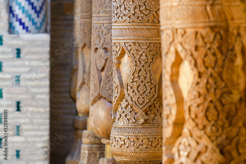 Old wooden pillars covered with carvings, details of decoration. Pahlavon Mahmud mausoleum, Khiva, Uzbekistan, Central Asia. photo