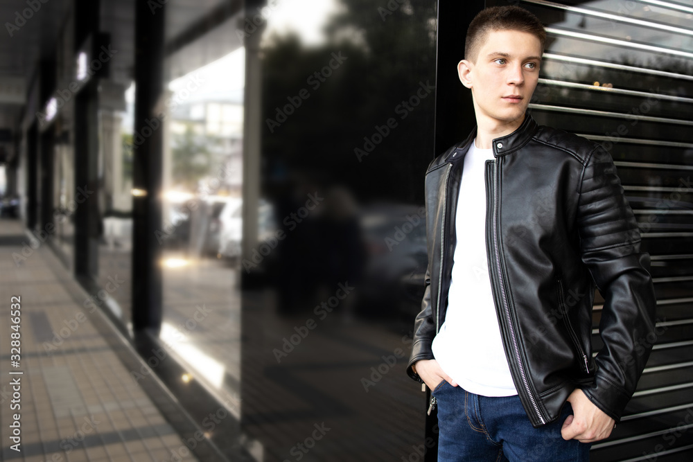 Street fashion. Glamor young man in black Leather Jacket at the city street. Stylish man go to clothing store. Fashion boutique. Street fashion. Glamor young man in black Leather Jacket at the city street. Stylish man go to clothing store. Fashion boutique.