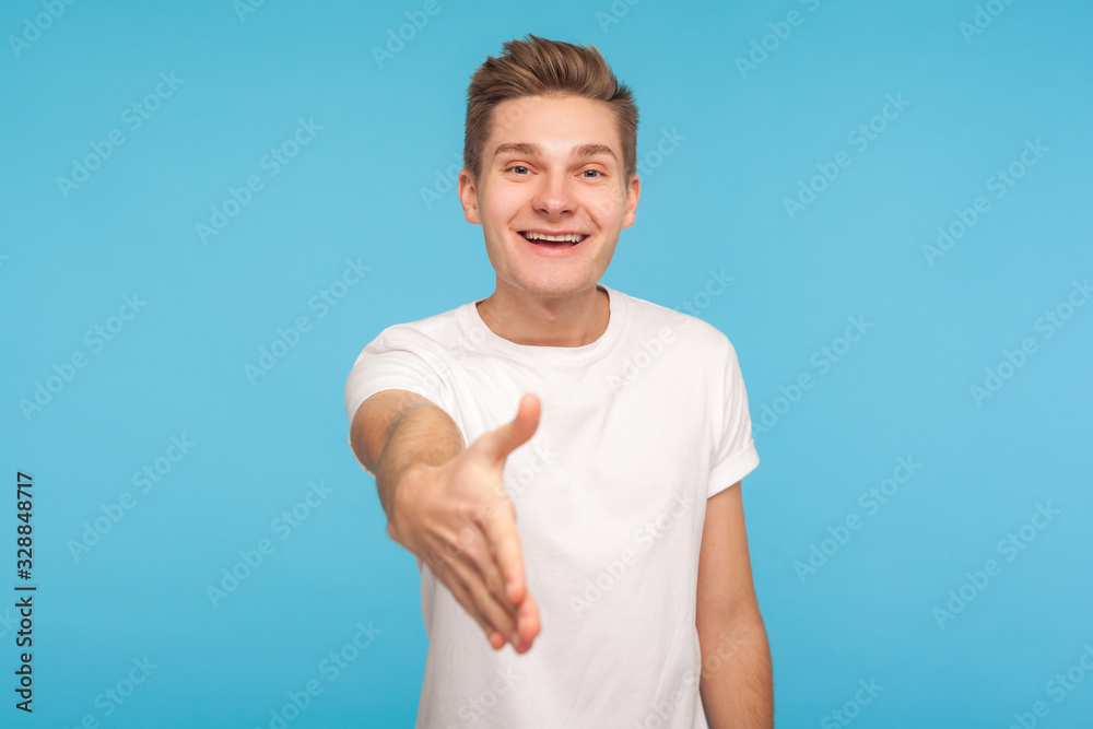Nice to meet you! Portrait of cheerful friendly hospitable man in casual white t-shirt giving hand to handshake, welcoming meeting with amiable smile. indoor studio shot isolated on blue background Nice to meet you! Portrait of cheerful friendly hospitable man in casual white t-shirt giving hand to handshake, welcoming meeting with amiable smile. indoor studio shot isolated on blue background