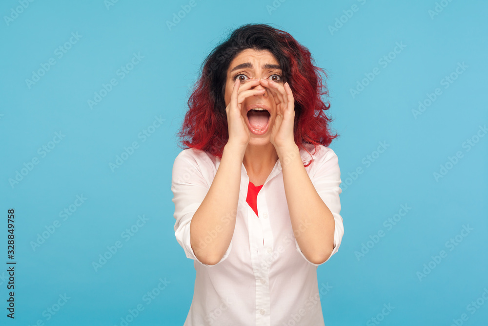 Attention, important message! Portrait of girl with fancy red hair in white shirt holding hands around mouth and shouting announcement, screaming loudly. indoor studio shot isolated on blue background Attention, important message! Portrait of girl with fancy red hair in white shirt holding hands around mouth and shouting announcement, screaming loudly. indoor studio shot isolated on blue background