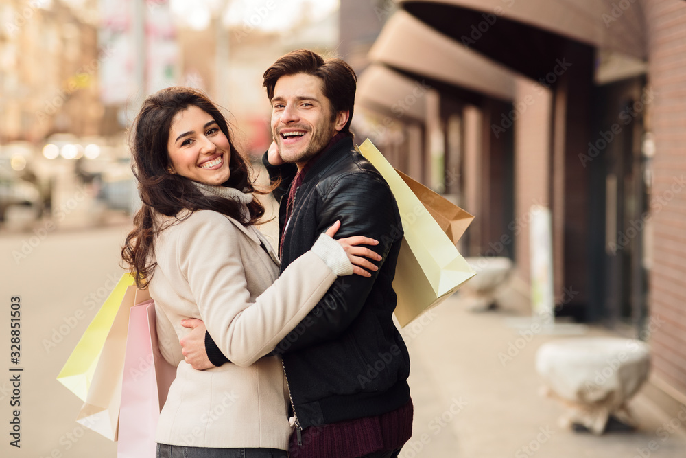 Young loving couple carrying paper shopping bags
