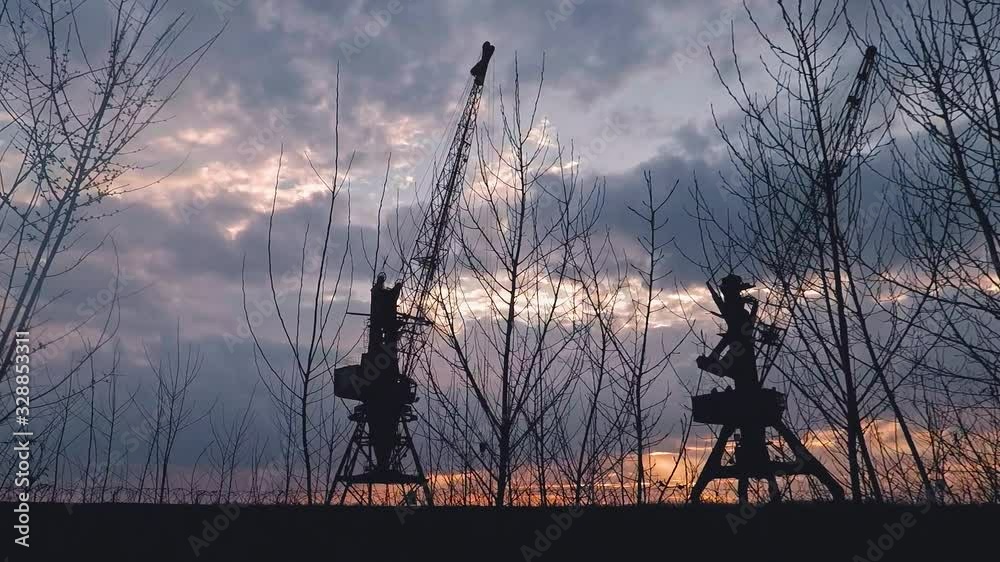 sunset in the port against the cloudy sky two large cranes