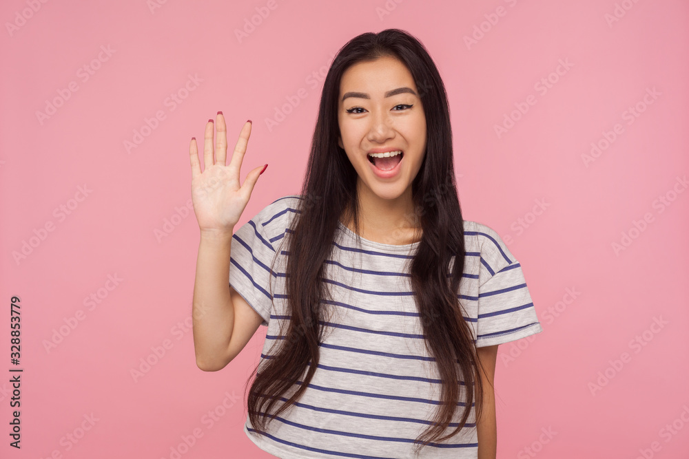 Hi! Portrait of friendly charming girl with long brunette hair in striped t-shirt saying hello and waving hand, joyfully welcoming, greeting guests. indoor studio shot isolated on pink background Hi! Portrait of friendly charming girl with long brunette hair in striped t-shirt saying hello and waving hand, joyfully welcoming, greeting guests. indoor studio shot isolated on pink background