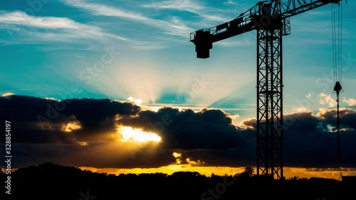 Beautiful Sunset with sun rays over the city with a crane silhouette, timelaps  photo