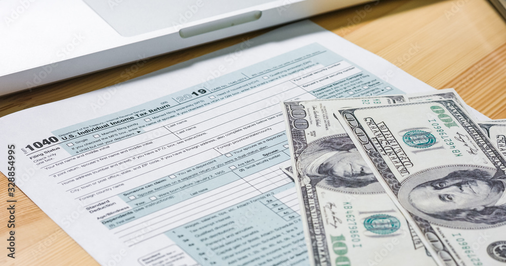 Obraz premium U.S. 1040 tax return form with 100 usd dollar bills.