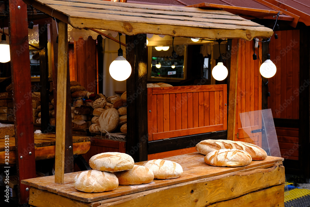 Round baguettes of Fresh Baked White Bread on a Wooden Table on Market.