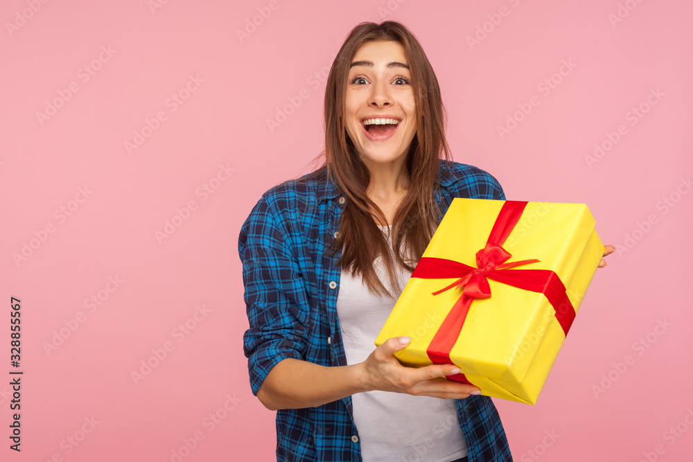 Unexpected present, holiday bonus! Portrait of surprised joyful pretty girl in checkered shirt holding wrapped box and smiling, looking amazed by birthday gift. indoor studio shot, pink background Unexpected present, holiday bonus! Portrait of surprised joyful pretty girl in checkered shirt holding wrapped box and smiling, looking amazed by birthday gift. indoor studio shot, pink background