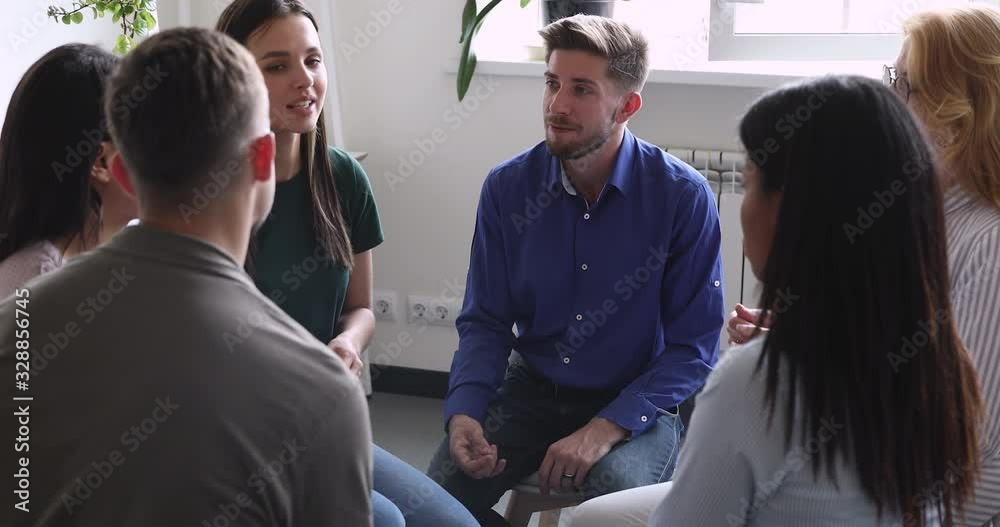 Diverse people sitting in circle, sharing personal problems at psychotherapy session. Male psychologist therapist helping multiracial younger and older patients at group therapy, rehab concept.