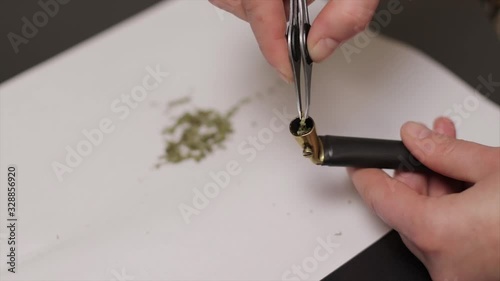 Closeup of young white female hands packing a pipe with marijuana to smoke