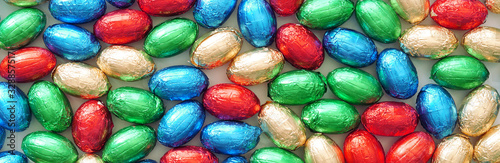 Close-up of pile of colorful candy Easter eggs wrapped in colored foil. colorful candies, panoramic view