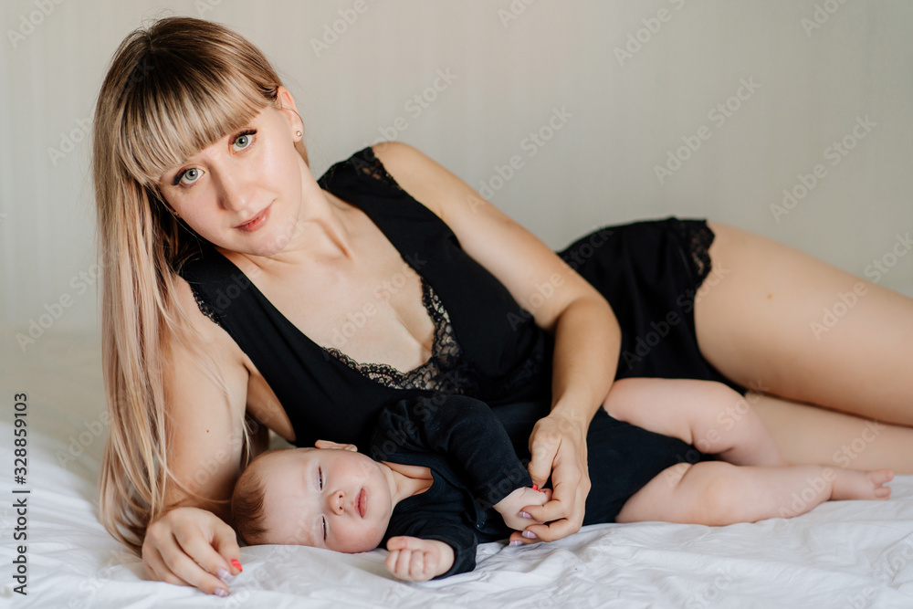 Obraz premium mom and baby in black lying together on bed