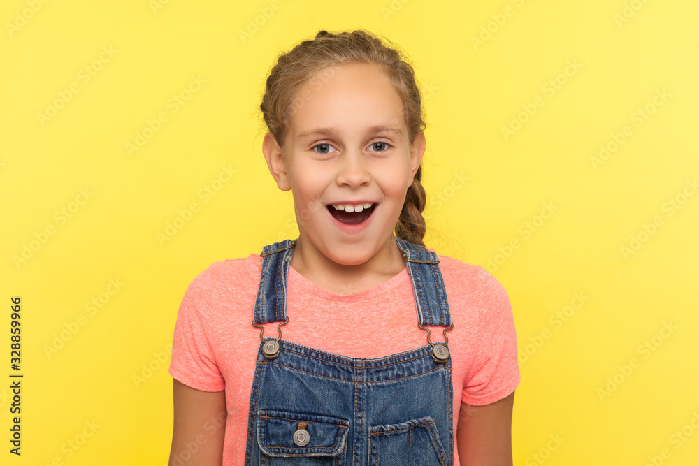 Wow, unbelievable! Portrait of surprised child in denim overalls standing with mouth open in surprise, expressing amazement, shocked by unbelievable news. studio shot isolated on yellow background Wow, unbelievable! Portrait of surprised child in denim overalls standing with mouth open in surprise, expressing amazement, shocked by unbelievable news. studio shot isolated on yellow background