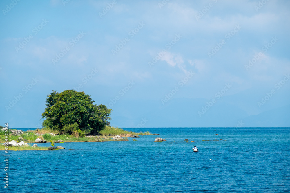 A Beautiful Green Island in the Beautiful Blue Tropical Waters of Lake Toba in Indonesia