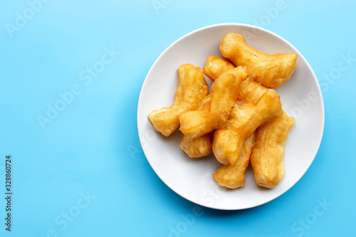 Deep-fried dough stick, chinese bread stick on white dish. Blue background