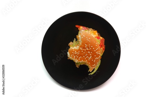 Eaten burger on a black plate, isolated on white background, top-down view