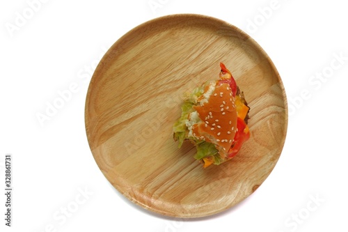 Top eye view of Bite a half piece scrap of delicious yummy layer burger chicken pepper,pork,beef,tomato,cheese,mayonnaise,lettuce in the wooden plate isolated on white table background at the kitchen
