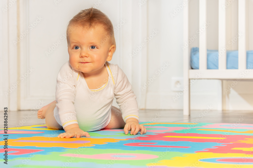 Toddler boy with calm positive face expression crawling on the carpet in nursery Toddler boy with calm positive face expression crawling on the carpet in nursery