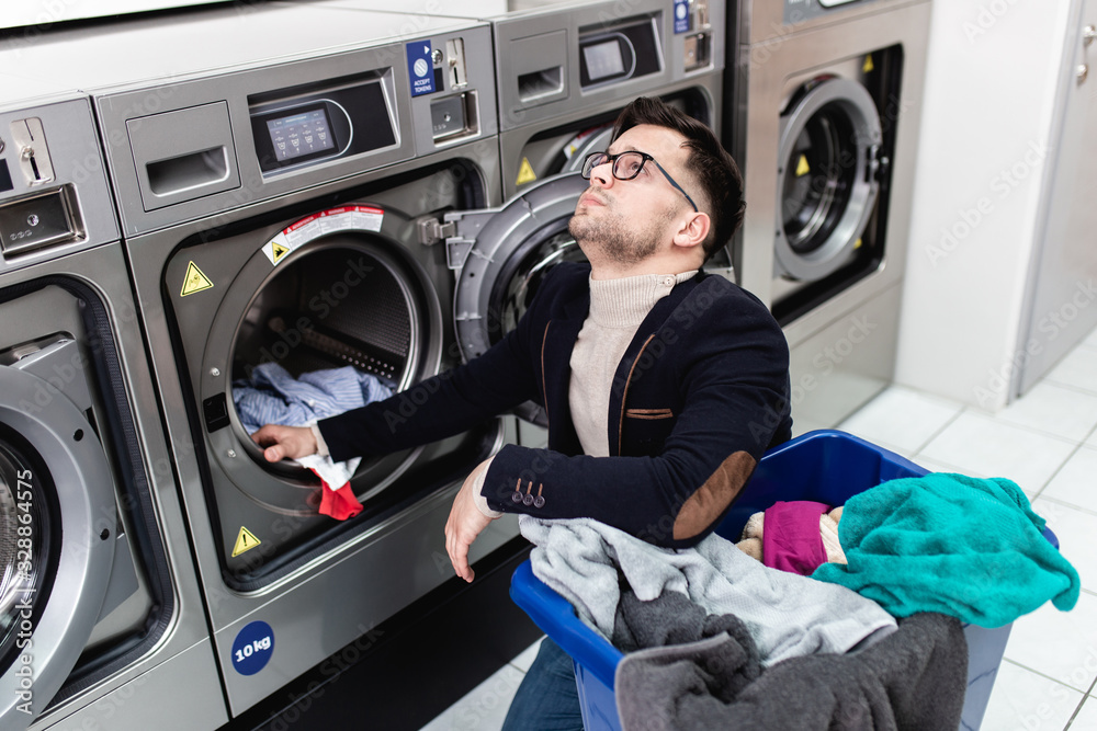 Handsome young businessman doing his weekly washing in a laundromat. Handsome young businessman doing his weekly washing in a laundromat.