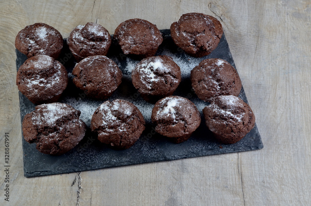 chocolate muffins on black stone plate and gray wood background, place for text chocolate muffins on black stone plate and gray wood background, place for text