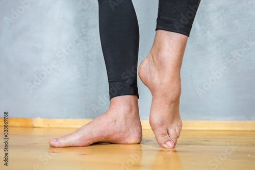 barefoot female feet in black leggings on a wooden floor