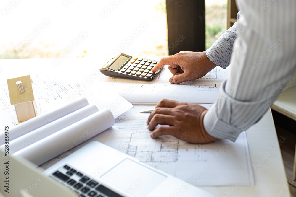 The engineer designed the house structure in the blueprint and working in the architect's room, There are equipment for designing laptops, pens, pencils, drawings And sample house with mold The engineer designed the house structure in the blueprint and working in the architect's room, There are equipment for designing laptops, pens, pencils, drawings And sample house with mold