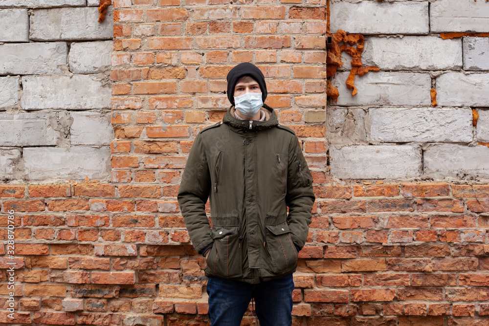 young guy in a medical mask near an abandoned building.respiratory viral disease epidemic covid-19 measles flu chickenpox young guy in a medical mask near an abandoned building.respiratory viral disease epidemic covid-19 measles flu chickenpox