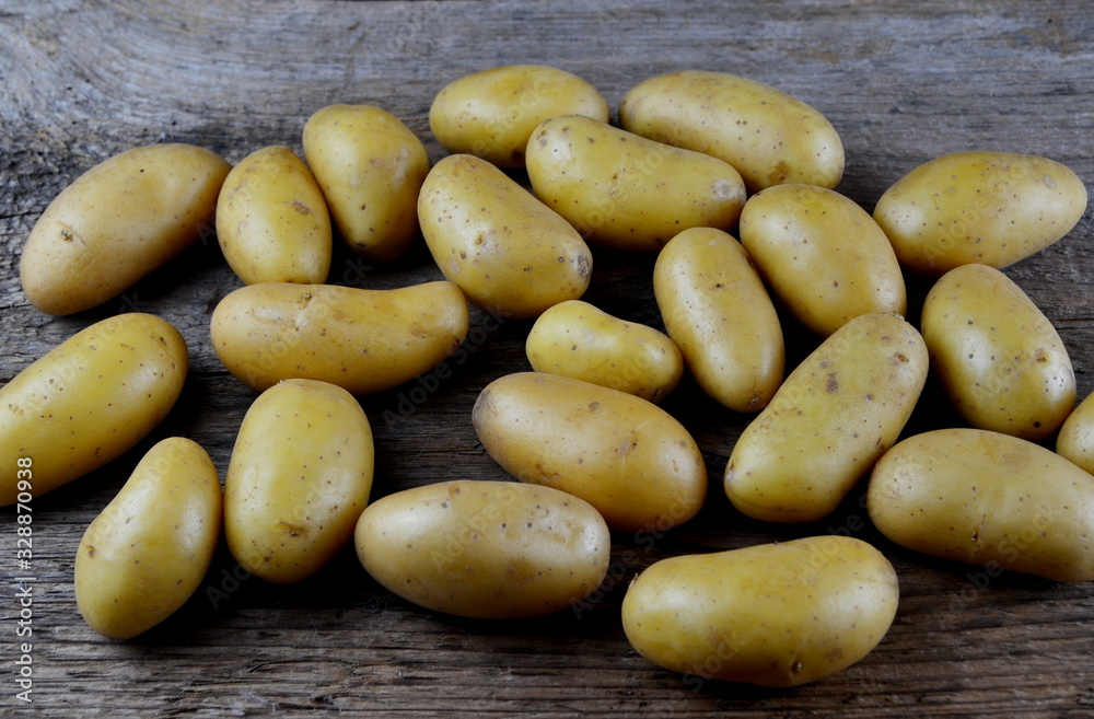 Raw potato food. Fresh baby potatoes in an old bag on a wooden board background. View from above Raw potato food. Fresh baby potatoes in an old bag on a wooden board background. View from above
