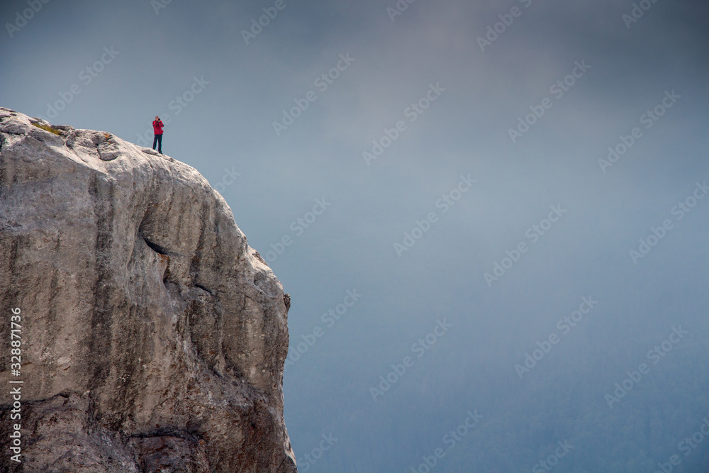 Hiker man standing on a cliff in Retezat National park in Carpathian mountain range, Romania