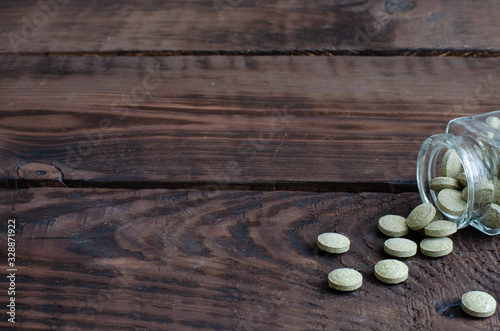 Small bottle with herbal pills on wooden background with copy space