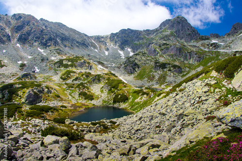 Magical alpine glacier lake, high mountains, cloudy sky, Retezat National Park, Carpathians, Romania, Europe