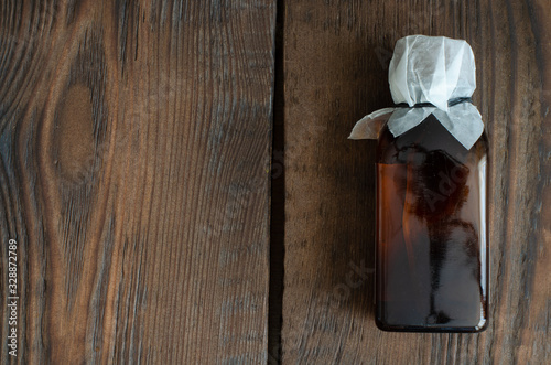 cough-drop in small dark bottle on wooden background with copy space.