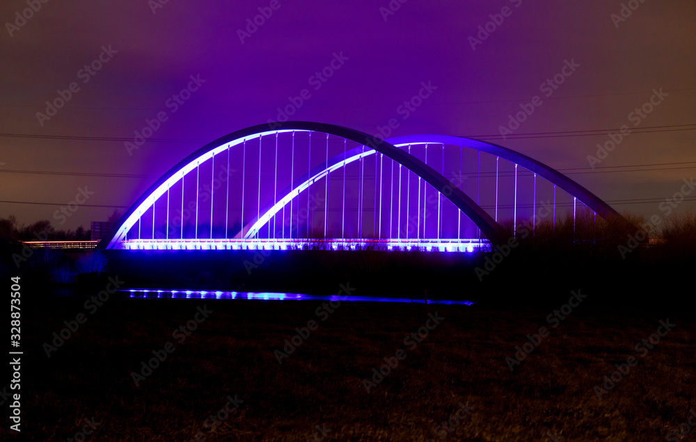 Obraz premium Long exposure of Toome bridge over the River Bann at night with blue and purple lights and some car red tail lights, Toomebridge, County Londonderry, Northern Ireland