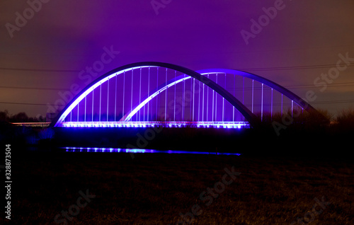Long exposure of Toome bridge over the River Bann at night with blue and purple lights and some car red tail lights, Toomebridge, County Londonderry, Northern Ireland