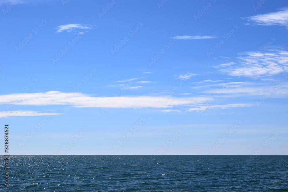 Incredibly beautiful view of the blue sky with white clouds over the sea. The water glistens in the sun.