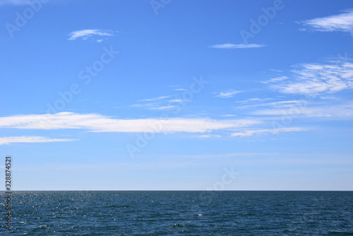 Incredibly beautiful view of the blue sky with white clouds over the sea. The water glistens in the sun.