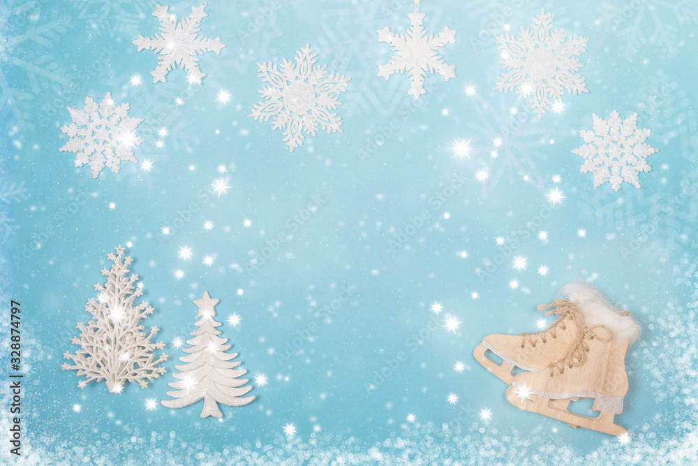 Winter seasonal flatlay with the ice skates and christmas trees on a blue background with and snow and snow flakes