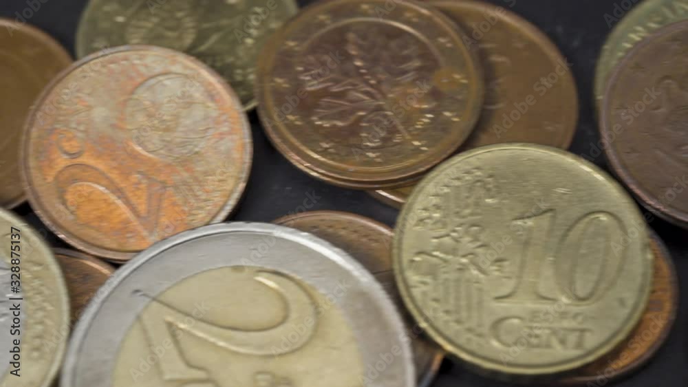 Closeup of European Union currency Euro or EUR coins on a dark slate plate background. Gentle panning shot. Closeup of European Union currency Euro or EUR coins on a dark slate plate background. Gentle panning shot.