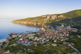 Aerial view of Komiza town on Vis island, Croatia in Dalmatia at sunrise. City laying on seaside in Mediterranean Sea surrounded by hills in summer vacation season.