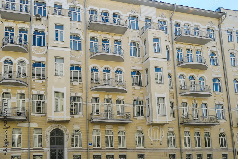 A yellow building with many ornate decors on the front facade. The building has many small windows and balconies. Very detailed construction.