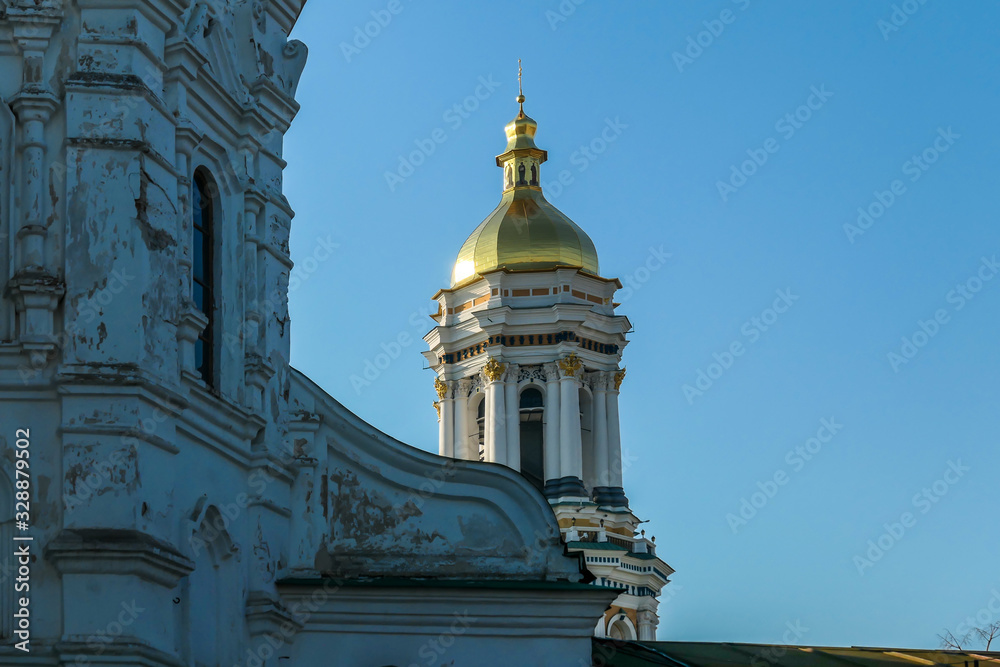 A close up on on of the rooftops of Kiev Pechersk Lavra complex, know also as Kiev Monastery of the Caves. The golden dome is shining bright with the sunlight. Clear and blue sky.