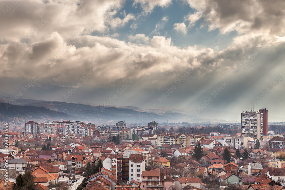 Beautiful sun rays casting light on Pirot cityscape during morning and cloudy, colorful sky