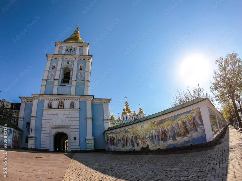 St Michael's Golden-Domed Cathedral in Kiev, Ukraine. The walls of the cathedral are painted blue and nicely decorated on each facade. Golden domes are reflecting the strong sun.