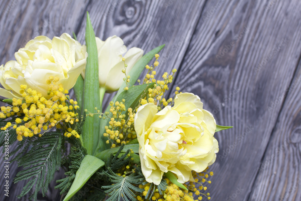 Bouquet of yellow tulips and mimosa. Against the background of brushed boards.