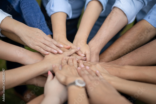 Close up to Asian people hold hand together in the middle of their group, friend with stack of hand showing the love and community of good friends.