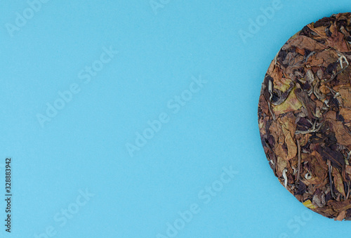 Pressed cake of chinese white tea on blue background with copy space photo